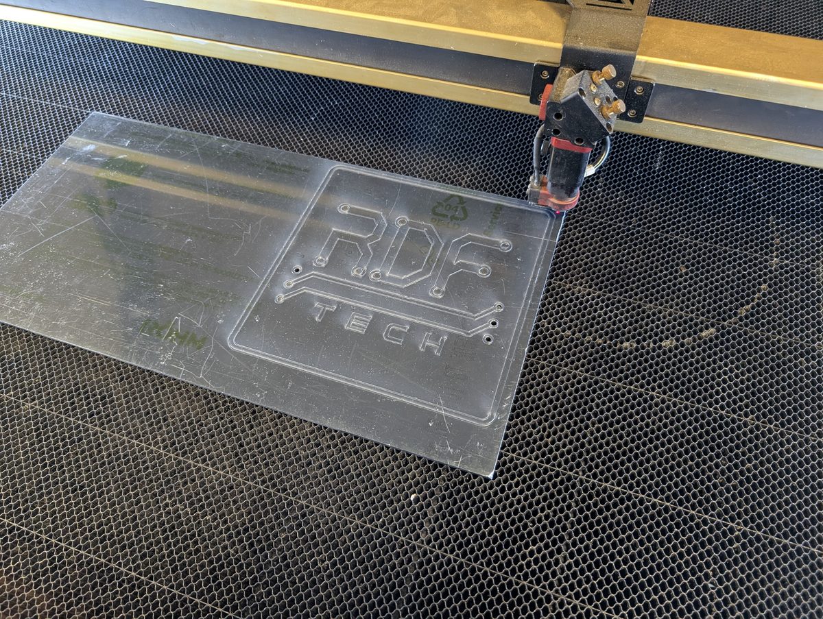 Graveuse/découpeuse laser CO₂ découpant le logo RDF Tech dans une plaque d'acrylique